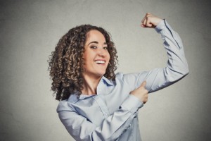 Fit young healthy woman flexing muscles showing her strength
