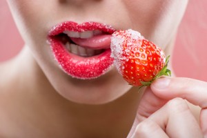 Beautiful female red lips, full with Granulated sugar, lick strawberry